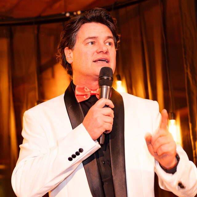 Keith De Meester met een microfoon op het podium